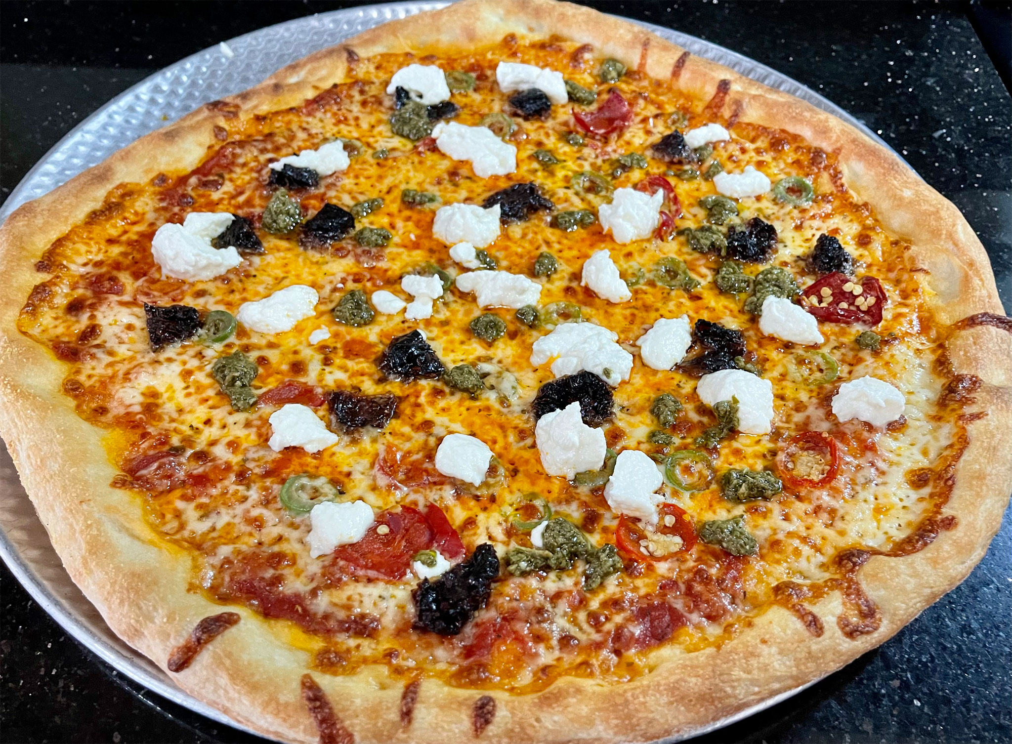 Pizza with sun dried tomatoes, cherry peppers Castelvetrano olives